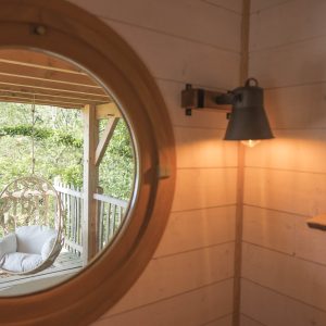 Hébergement insolite en Bretagne : cabane avec vue, hamac suspendu et lumière chaleureuse.