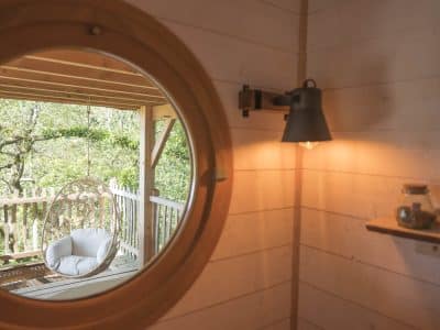 Hébergement insolite en Bretagne : cabane avec vue, hamac suspendu et lumière chaleureuse.