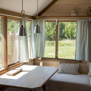 Cabane en bois en Bretagne, avec grandes fenêtres et vue sur la nature verdoyante.