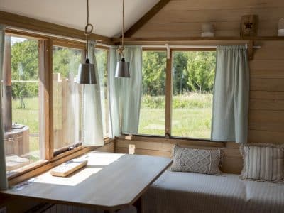 Cabane en bois en Bretagne, avec grandes fenêtres et vue sur la nature verdoyante.