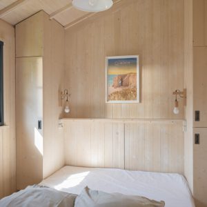 Chalet en bois lumineux en Bretagne, avec lit simple et décor minimaliste.