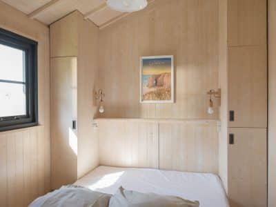 Chalet en bois lumineux en Bretagne, avec lit simple et décor minimaliste.