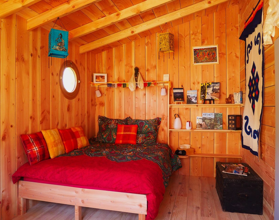 Cabane en bois cosy avec lit coloré et décor chaleureux en Auvergne-Rhône-Alpes.