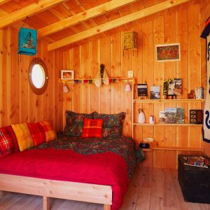 Cabane en bois cosy avec lit coloré et décor chaleureux en Auvergne-Rhône-Alpes.