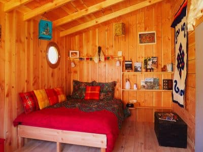 Cabane en bois cosy avec lit coloré et décor chaleureux en Auvergne-Rhône-Alpes.