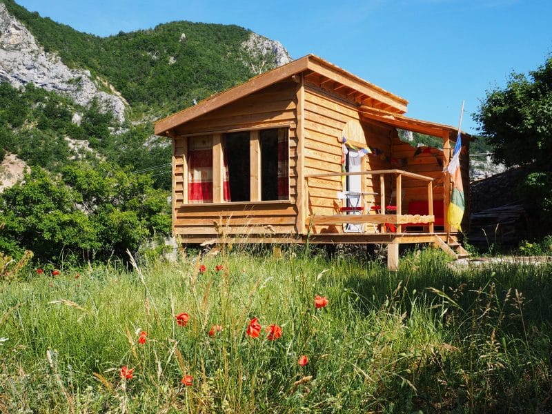 Chalet en bois entouré de fleurs sauvages et de montagnes verdoyantes.
