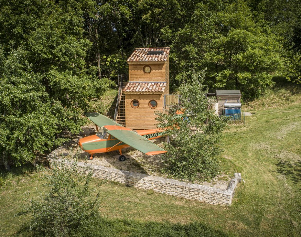 Cabane dans les arbres avec un avion en bois, entourée de verdure à Languedoc-Roussillon.