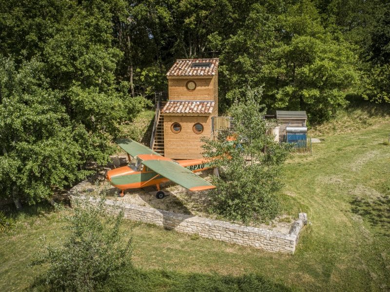 Cabane dans les arbres avec un avion en bois, entourée de verdure à Languedoc-Roussillon.