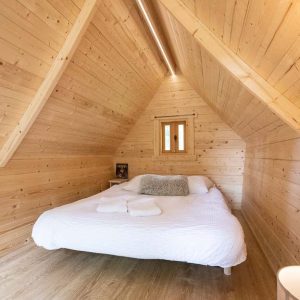 Cabane en bois cosy avec lit douillet et murs en bois clair à Champagne-Ardenne.