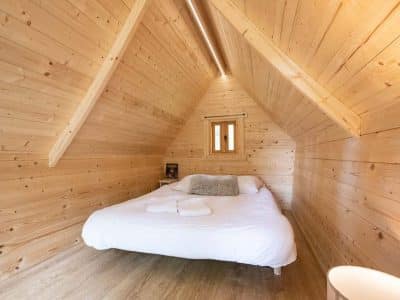 Cabane en bois cosy avec lit douillet et murs en bois clair à Champagne-Ardenne.