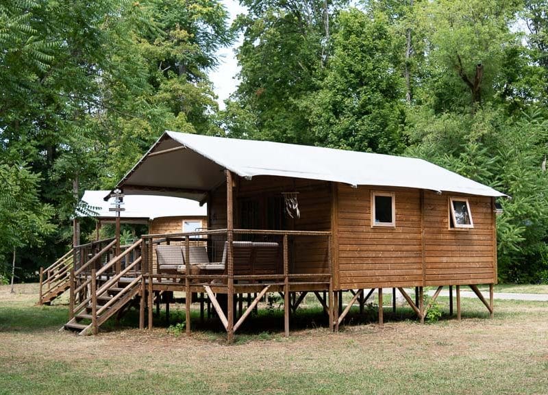 Cabane en bois sur pilotis, entourée de verdure, idéale pour un séjour insolite.