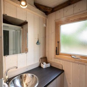 Hébergement insolite en bois à Champagne-Ardennes avec lavabo design et lumière chaleureuse.