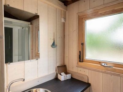 Hébergement insolite en bois à Champagne-Ardennes avec lavabo design et lumière chaleureuse.
