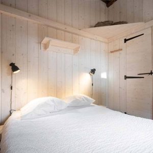Chalet en bois à Champagne-Ardennes, avec un lit douillet et des murs clairs.
