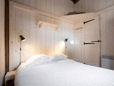 Chalet en bois à Champagne-Ardennes, avec un lit douillet et des murs clairs.