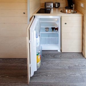 Intérieur dun hébergement insolite en bois avec kitchenette et réfrigérateur.