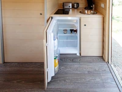 Intérieur dun hébergement insolite en bois avec kitchenette et réfrigérateur.