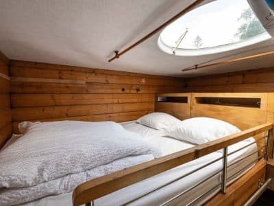 Chalet en bois cosy avec lit double et fenêtre ronde pour admirer les étoiles.