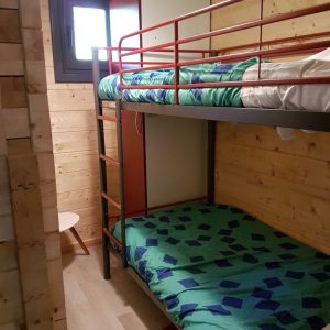 Chambre en bois avec lits superposés, décor coloré et ambiance chaleureuse.