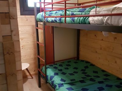 Chambre en bois avec lits superposés, décor coloré et ambiance chaleureuse.
