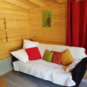 Cabane en bois à Champagne-Ardennes, avec un canapé coloré et des coussins décoratifs.