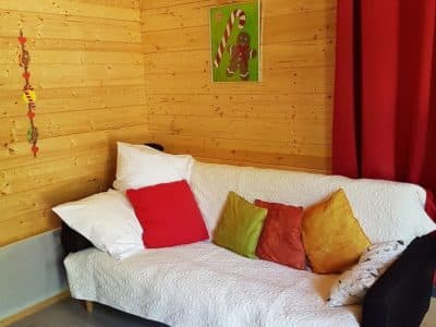Cabane en bois à Champagne-Ardennes, avec un canapé coloré et des coussins décoratifs.