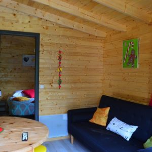 Chalet en bois à Champagne-Ardennes, intérieur chaleureux avec canapé et décoration colorée.