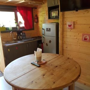 Chalet en bois à Champagne-Ardennes avec cuisine équipée et table ronde colorée.