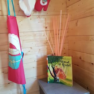 Cabane en bois à Champagne-Ardenne, décor cosy avec livre et accessoires de cuisine.