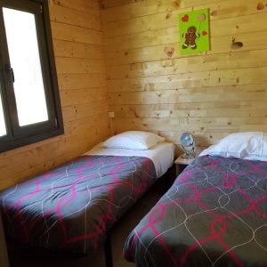 Chalet en bois à Champagne-Ardennes, avec deux lits simples et une décoration chaleureuse.