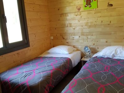 Chalet en bois à Champagne-Ardennes, avec deux lits simples et une décoration chaleureuse.
