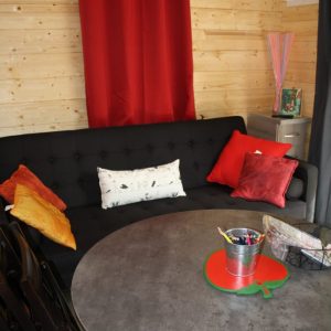 Hébergement insolite à Champagne-Ardennes : chalet en bois avec canapé et décor coloré.