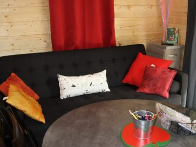 Hébergement insolite à Champagne-Ardennes : chalet en bois avec canapé et décor coloré.