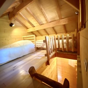 Cabane en bois chaleureuse avec mezzanine et lumière douce, idéale pour un séjour unique.