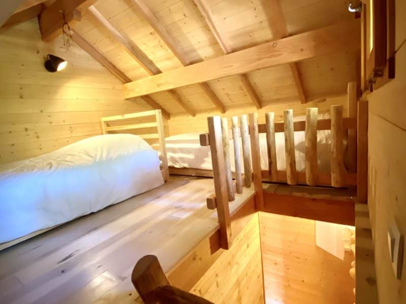 Chalet en bois chaleureux avec mezzanine et éclairage doux. Parfait pour un séjour cocooning.