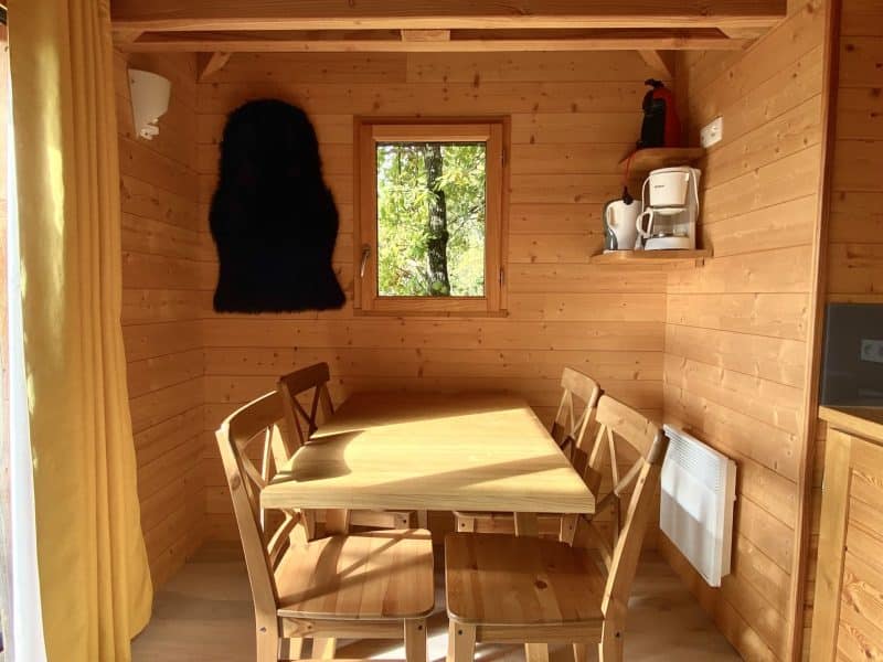 Chalet en bois chaleureux avec table en bois et lumière naturelle.