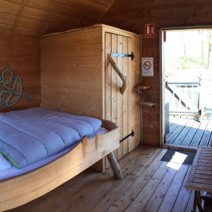 Cabane en bois chaleureuse avec lit douillet et vue sur la nature.
