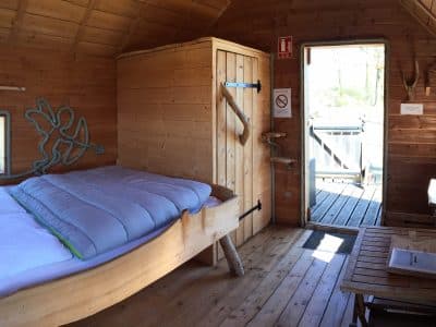 Cabane en bois chaleureuse avec lit douillet et vue sur la nature.