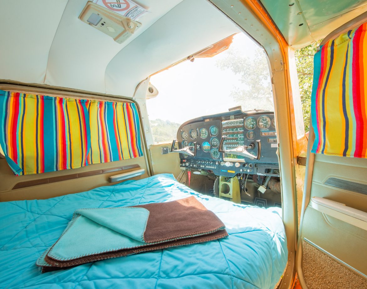 Hébergement insolite : chambre dans un avion vintage avec rideaux colorés.