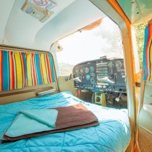 Hébergement insolite : chambre dans un avion vintage avec rideaux colorés.