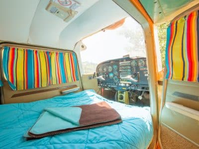 Hébergement insolite : chambre dans un avion vintage avec rideaux colorés.