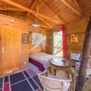 Cabane en bois chaleureuse avec lit douillet et vue sur la nature.