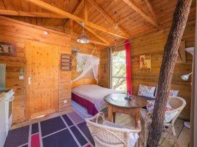 Cabane en bois chaleureuse avec lit douillet et vue sur la nature.