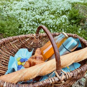 Panier pique-nique en osier avec croissant et baguette, au cœur de la Bretagne.