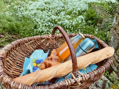 Panier pique-nique en osier avec croissant et baguette, au cœur de la Bretagne.