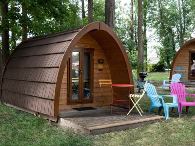 Cabane en bois à Champagne-Ardenne, avec chaises colorées et verdure environnante.