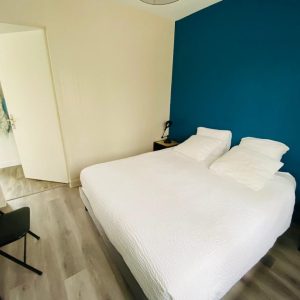 Chambre dhôtes moderne à Champagne-Ardennes, avec mur bleu et lit confortable.