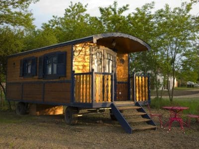 Charmante roulotte en bois avec terrasse, entourée de verdure en Auvergne.
