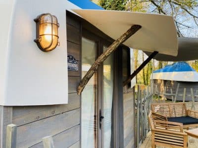 Hébergement insolite en bois à Champagne-Ardenne, avec terrasse en bois et éclairage vintage.