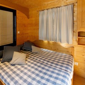 Chalet en bois à Champagne-Ardennes, avec lit à baldaquin et rideaux rayés.